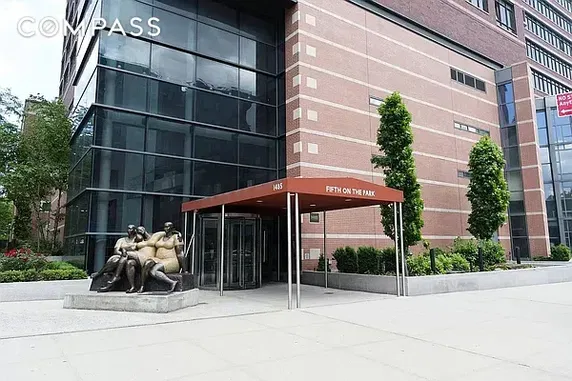 Front view of a modern multi-story building with a glass facade and brick exterior.