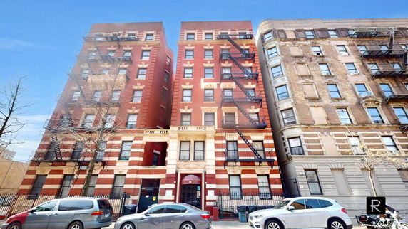 Front view of a multi-story brick apartment building with fire escapes.