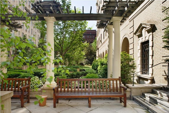 Garden area viewed from an outdoor perspective with benches, columns, and an adjacent building facade.