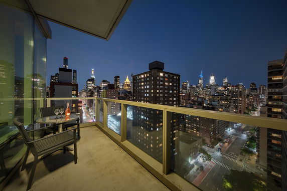 Cityscape view with buildings and streets illuminated at night, seen from a balcony.