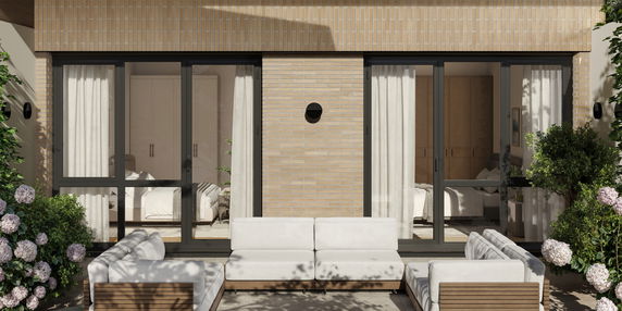 Front view of a modern house with large glass doors and outdoor seating area.