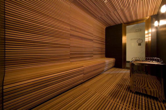 Interior view of a modern sauna with wooden slats and a metal heater.
