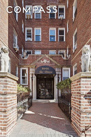 Front view of a brick residential building entrance with decorative stone statues.