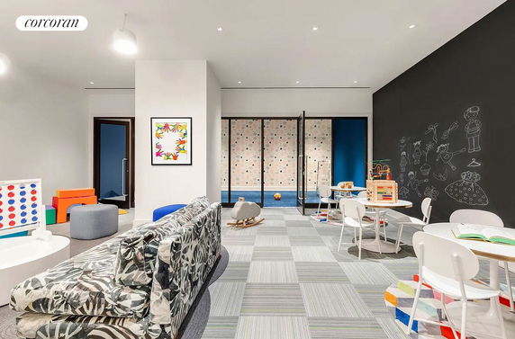Interior of an indoor play area with toys, a chalkboard wall, and a sitting area.