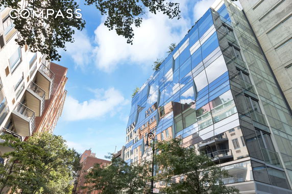 Front view of a modern glass-walled building with reflections of the surroundings.