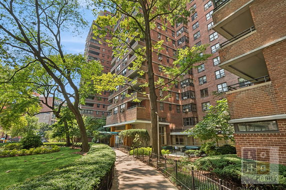 Front view of a multi-story building with brick facade and balconies.
