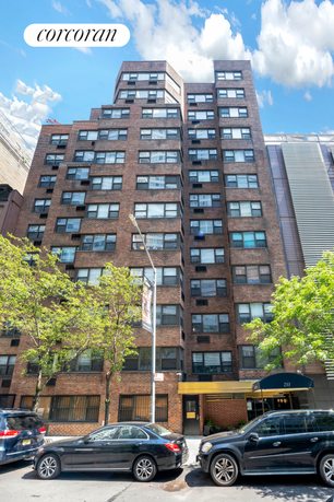 Front view of a multi-story brick building with large windows.