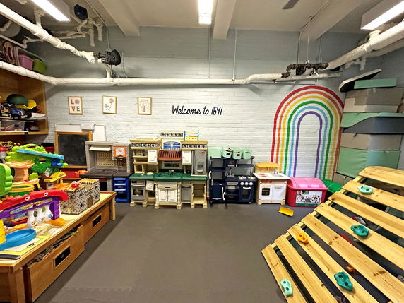Indoor play area with toys and play equipment arranged in a room.