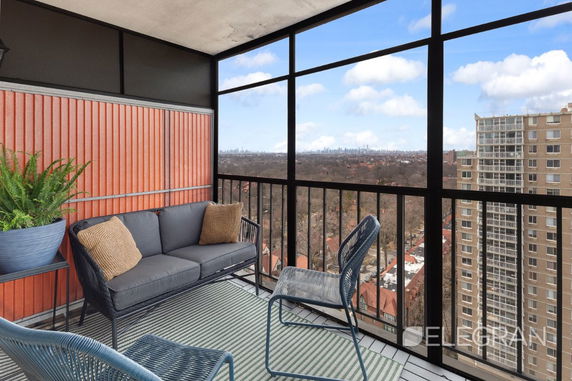 Panoramic view of the city skyline from a balcony with outdoor seating.