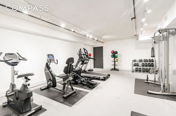Indoor gym area with exercise equipment and weights.