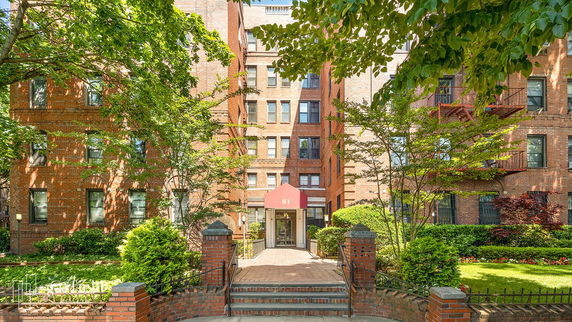 Front view of a multi-story brick building with a red awning at the entrance.