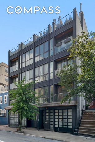 Front view of a modern multi-story building with large windows and a rooftop terrace.