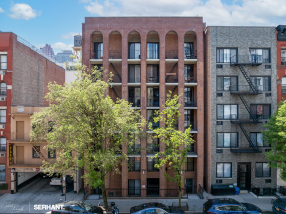 Front view of a multi-story brick apartment building with balconies.