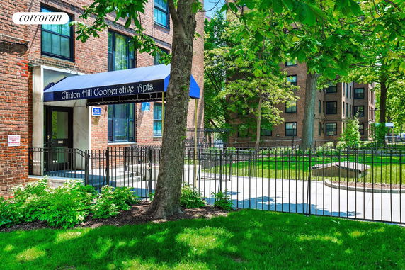 Front view of a cooperative apartment building entrance with a blue awning.