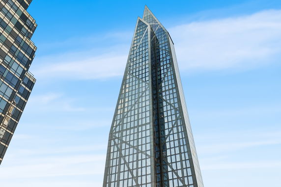 Modern glass skyscraper with a unique triangular design.
