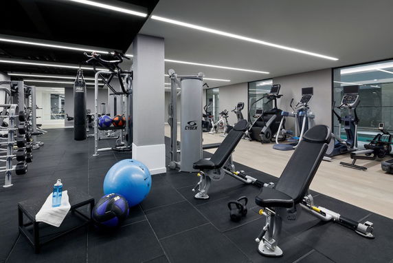 Interior view of a gym with various fitness equipment including benches, exercise machines, and weights.