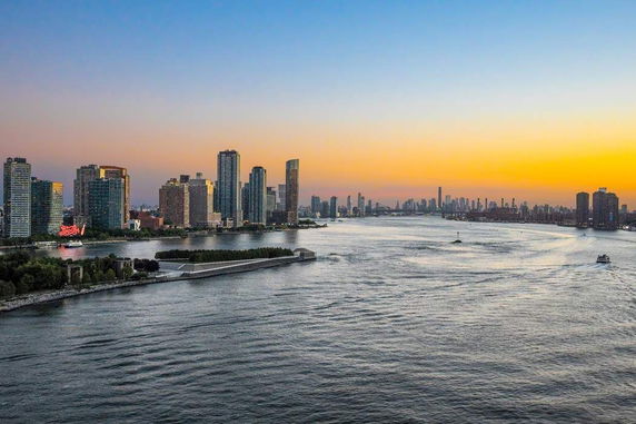Panoramic view of a city skyline with river in the foreground during sunset.