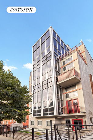 Front view of a multi-story modern building with large windows and metal balconies.