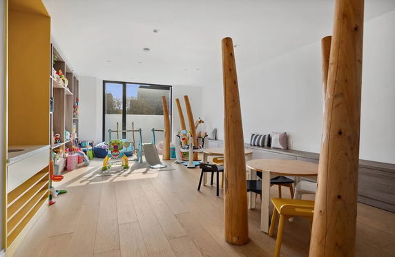 Indoor play area with toys and wooden pillars.