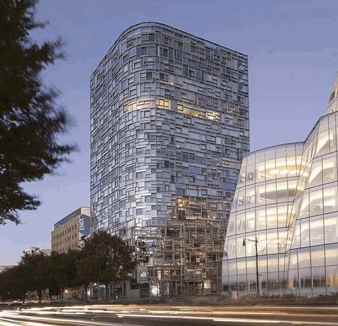 Front view of a modern glass building with a unique geometric facade.