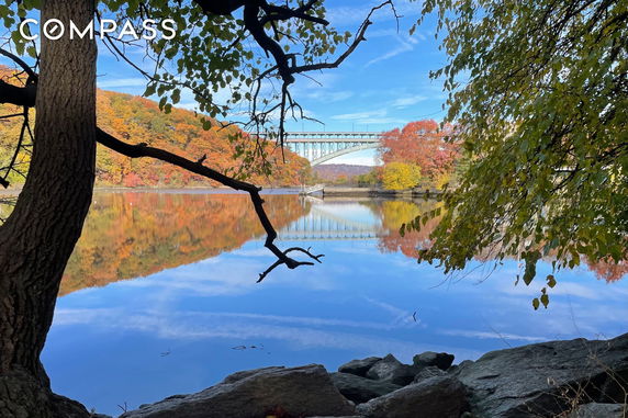 Scenic view of a river reflecting autumn trees and a bridge.