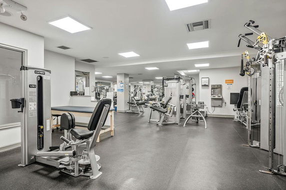 Indoor gym area with various exercise equipment and machines.