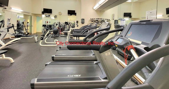 Interior view of a gym area with various exercise equipment including treadmills and weight machines.
