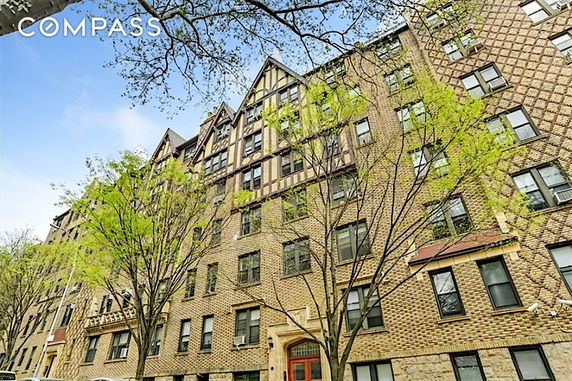 Front view of a multi-story brick apartment building with prominent gables.