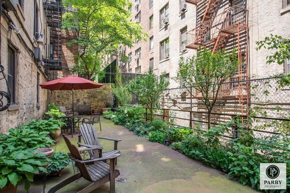 Outdoor courtyard with seating area and surrounding buildings with fire escapes.