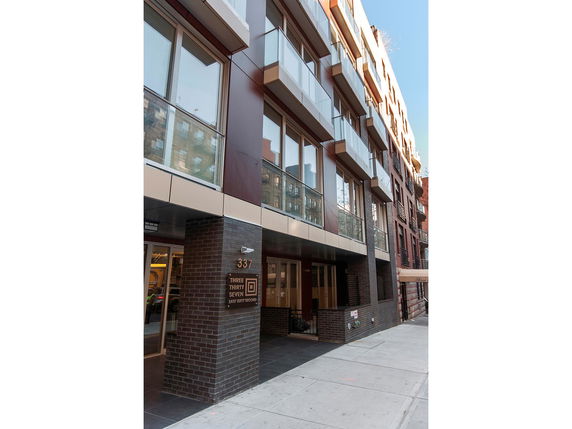 Front view of a modern multi-story building with large glass windows and balconies.