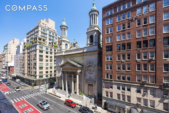 Front view of a grand historic building with classical architectural features and surrounding city buildings.