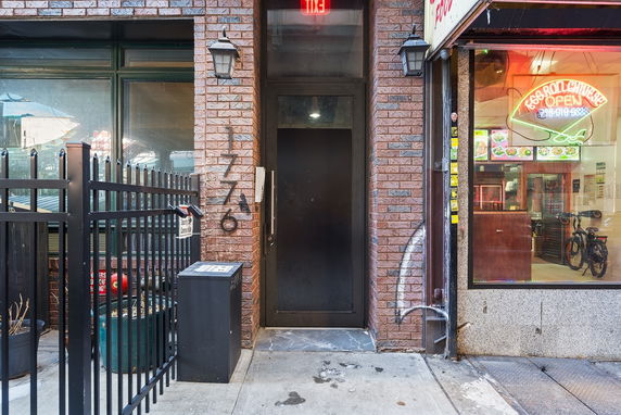 Entrance view of a brick building with a black metal door and adjacent restaurant.