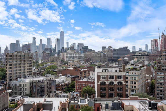 Panoramic view of city buildings and skyline under a cloudy sky.