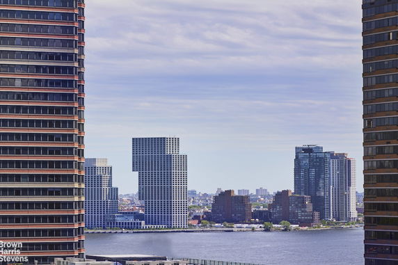 Panoramic view of city buildings and river visible between two tall structures.