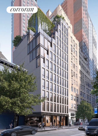 Front view of a modern multi-story building with glass windows and greenery on top.