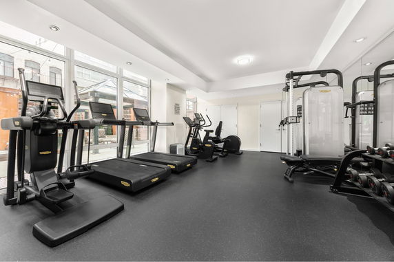 Interior view of a gym with exercise equipment including treadmills and weight machines.