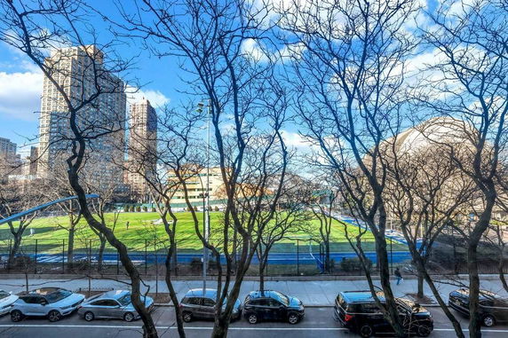View of buildings and a sports field through bare trees