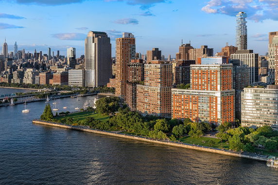 Aerial view of a cityscape with skyscrapers and waterfront park area.