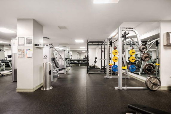 Indoor gym area with exercise equipment and weights.