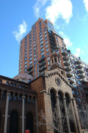 Front view of a high-rise apartment building attached to a historic church structure.