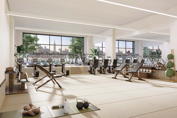 Interior view of a gym area with workout equipment and large windows.