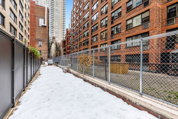 Rooftop area of a building with snow-covered surface and fenced perimeter.