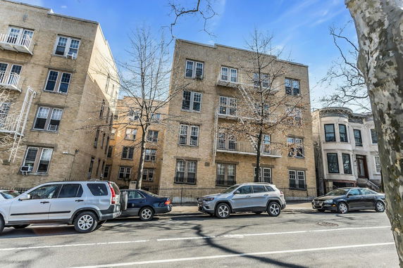 Front view of a multi-story apartment building with fire escapes.