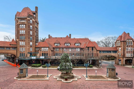 Front view of a large historic building with red-tiled roofs and a tower.