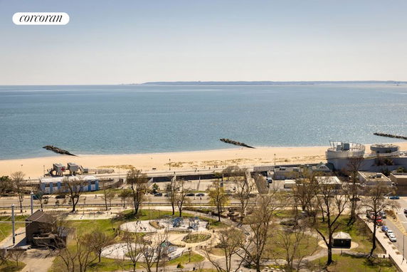 Panoramic view of a coastal area with a beach, ocean, and nearby buildings.
