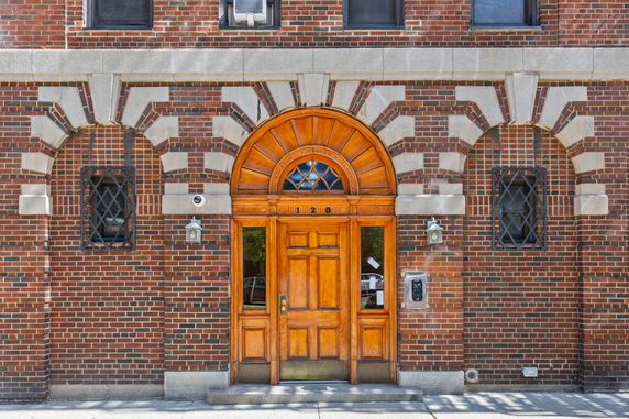 Front view of a brick building with a wooden arched doorway.