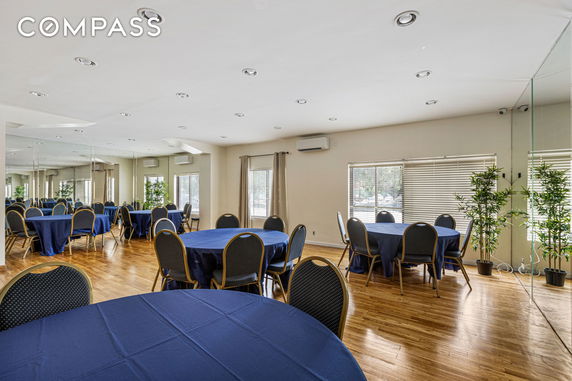 Indoor room with round tables covered with blue tablecloths and chairs, suitable for gatherings.