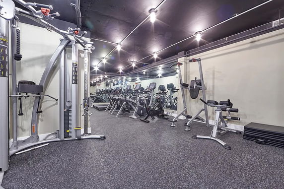 Indoor gym area with various exercise equipment and mirrors.