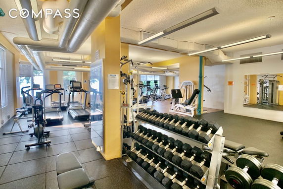 Indoor gym area with exercise equipment including treadmills, weights, and exercise machines.