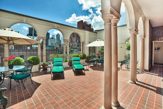 Rooftop terrace with lounge chairs, tables, and parasols.